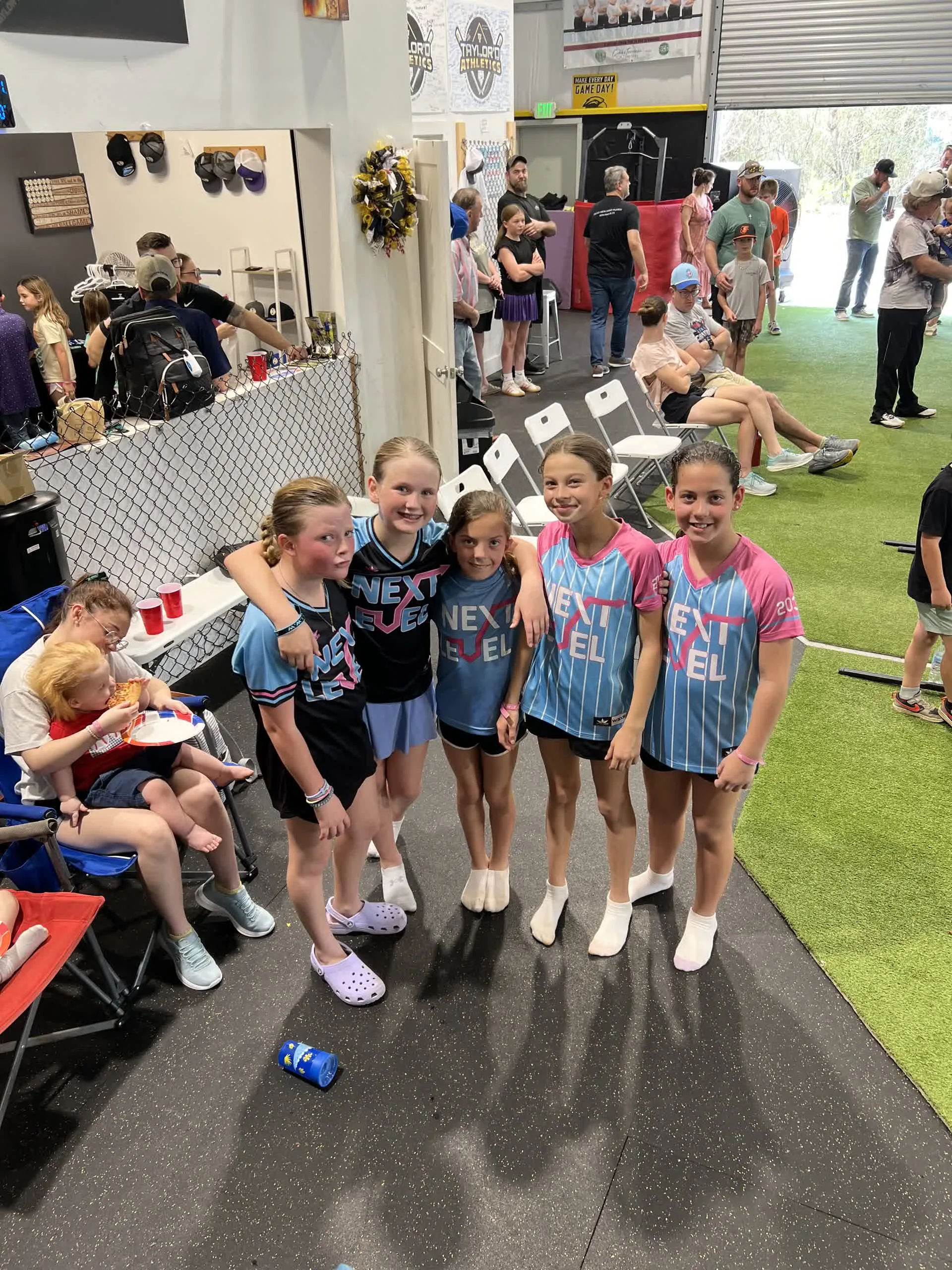 Girls in softball jerseys smiling together at a birthday party