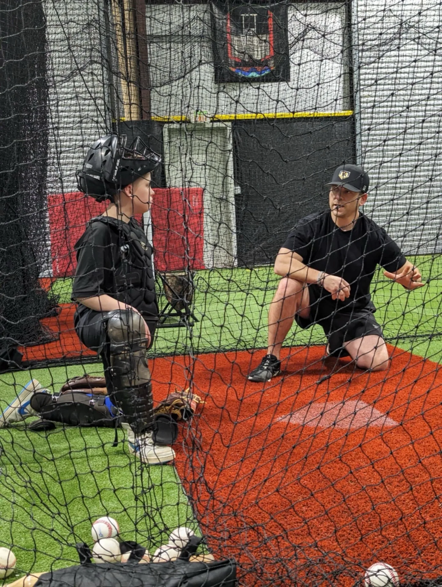 Coach working with a catcher in full gear during a private session