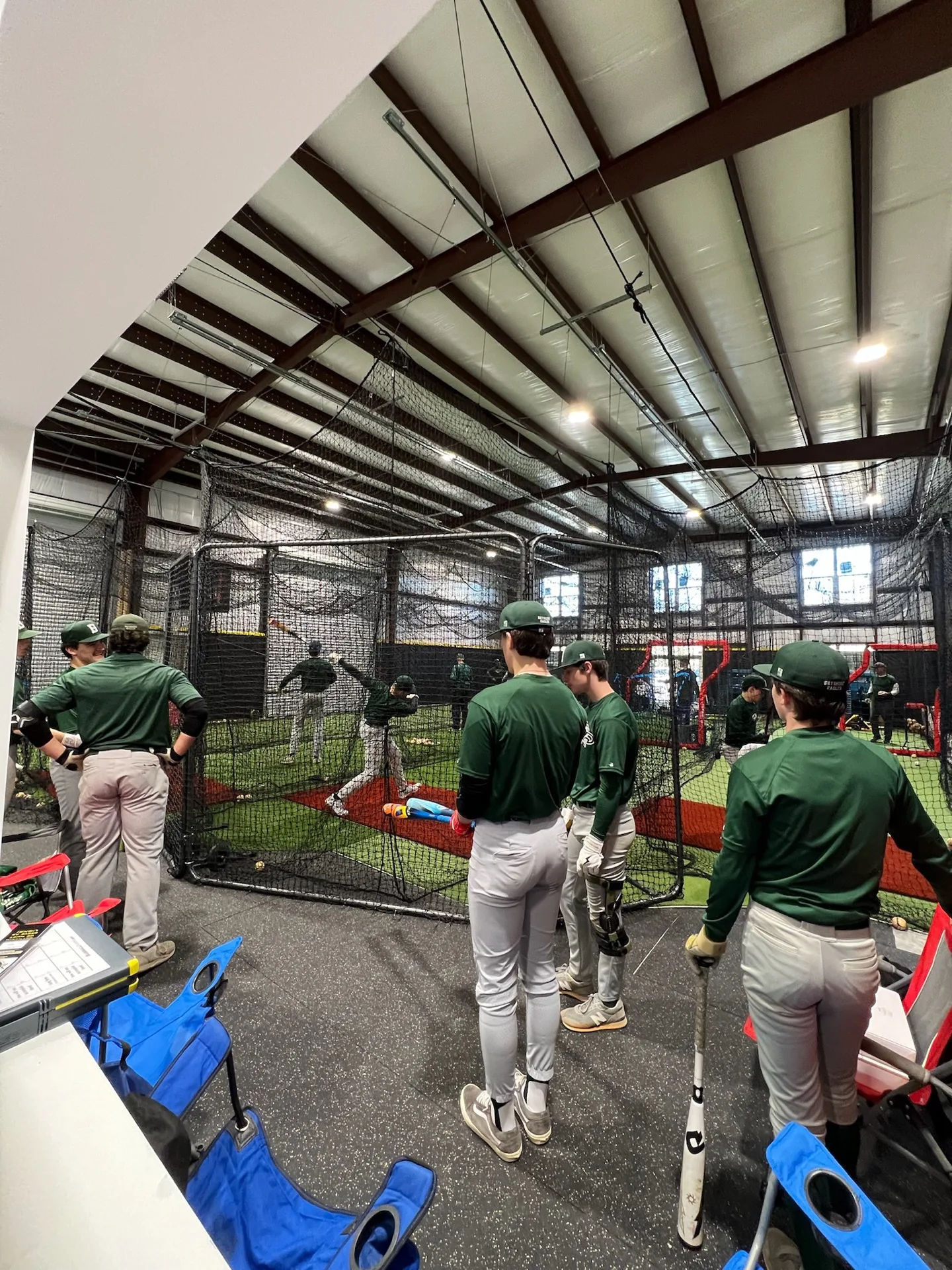 High school team in green uniforms training in the batting cages