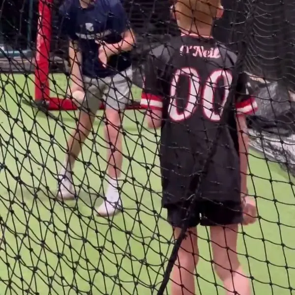 Two young kids in the batting cage together